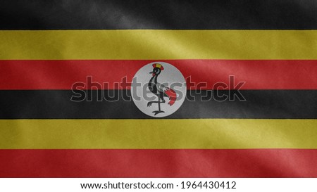 Ugandan flag waving in the wind. Close up of Uganda banner blowing, soft and smooth silk. Cloth fabric texture ensign background