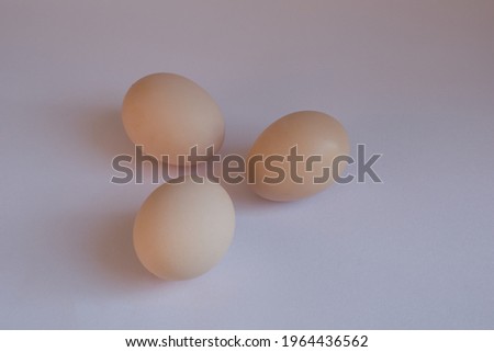 picture of three light yellow eggs in triangle shape in isolated white background.