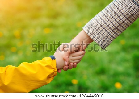 Mother and child hands reaching to each other. Support, help and trust. Parent holds the hand of a child on a walk. Kid and mother hands on nature background. Love, relationship and teamwork in family Royalty-Free Stock Photo #1964445010