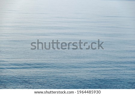 Calm Water blurred Surface. Textured sea water with fine ripples.  Ocean merges into the sky.  Defocused photo with blur in motion.