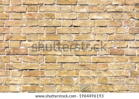 Texture of a very old brick wall made of ancient rough stones. Weathered brick wall texture background in sunlight. A high resolution.