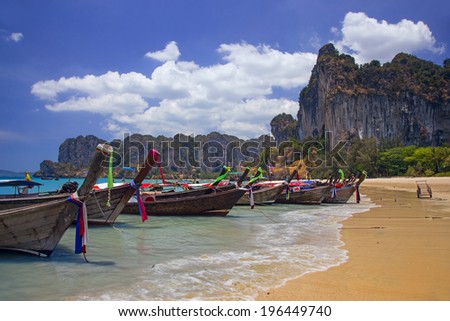 Longtail boats landing at Railay bay, Thailand. Picturesque rocks on the background