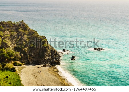 People on sandy beach sea shore, rocky shoreline, Andalucia Spain.
