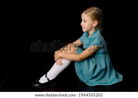 Cute girl sitting on floor hugging her knees