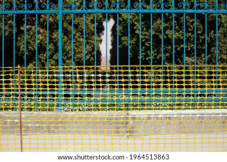 The fence is forged ancient blue and the fence is temporary yellow