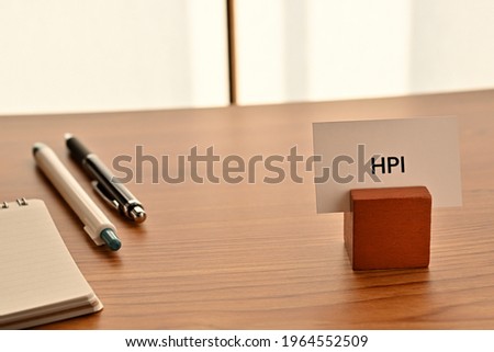 There is a card on paper stand with the word of HPI which is an abbreviation for Human Performance Improvement on the desk with a pen.