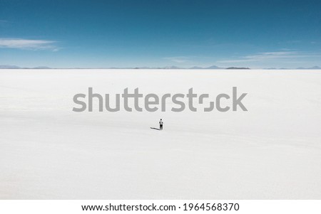 One isolated male tourist enjoying endless boundless infinite vastness width expanse of white salt flat lake Salar de Uyuni in Potosi Bolivia South America Royalty-Free Stock Photo #1964568370