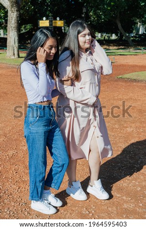 Two latin female friends walking in the park. Freindship concept.
