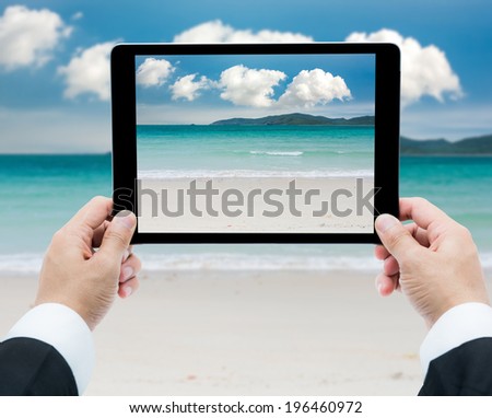 Businessman hands tablet taking pictures beach and sea on cloud