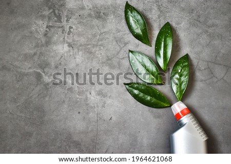 Gray bottle for cleaning. Eco bottle for safe cleaning with green leaves on a concrete background. Copy space, flat lay. Creative composition.