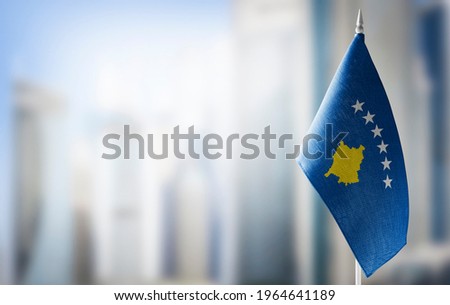 A small flag of Kosovo on the background of a blurred background