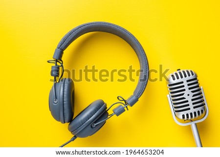 Vintage microphone and headphones on yellow background. Top view.