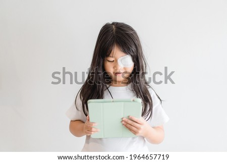 Lazy Eye amblyopia in children.Eye care.Little asian girl covered up with a special patch online learning at home.Occlusion therapy using an eye patch.Children care.child online learning education. Royalty-Free Stock Photo #1964657719