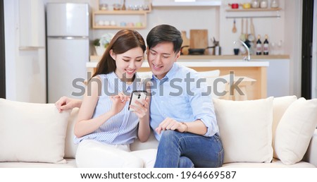 asian couple looking some information on the internet together with smart phone at home happily