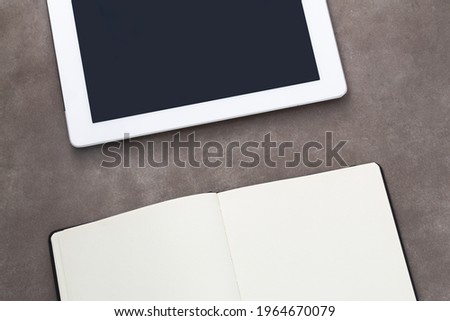 White tablet computer and paper notepad on grunge background