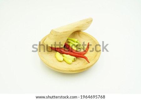 Fresh red and green chilies on a wooden mortar base isolated on a white background