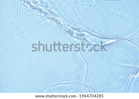 De-focused blurred transparent blue colored clear calm water surface texture with splashes and bubbles. Trendy abstract nature background. Water waves in sunlight with copy space. Royalty-Free Stock Photo #1964704285