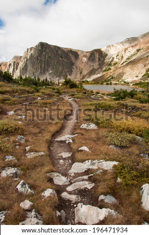 A high mountain hiking trail winds through the Medicine Bow Mountains of southern Wyoming beneath a gray early autumn sky.