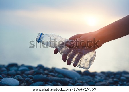 Volunteer man and plastic bottle, clean up day, collecting waste on sea beach, pollution and recycling concept Royalty-Free Stock Photo #1964719969
