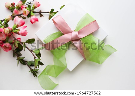 greeting card mockup. flowering branch and gift box with a bow on a white background. congratulation. invitation 