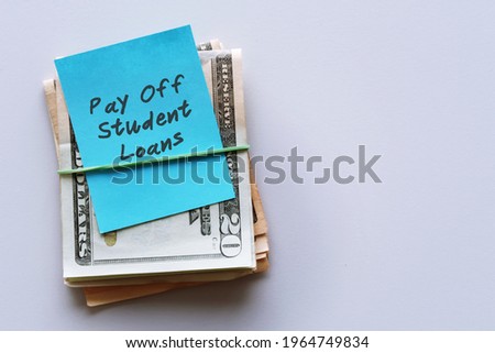 Cash dollars money with blue note written Pay Off Student Loans , concept of financial management strategy .set aside amount money to pay more than minimum , extra payment to help pay off faster Royalty-Free Stock Photo #1964749834