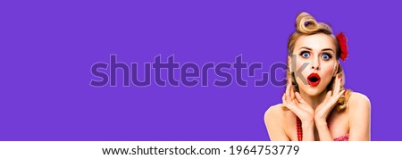 Unbelievable news! Excited surprised, very happy blondy hair woman. Pin up syle girl with opened mouth and raised hands. Retro and vintage concept. Violet purple color background. Wide composition.