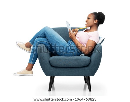 comfort, people and furniture concept - happy smiling young african american woman sitting in modern armchair writing to notebook over white background