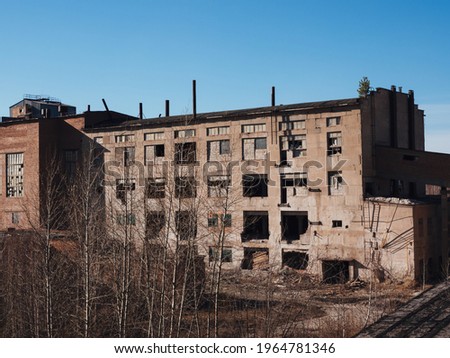 An old abandoned factory building in early autumn. post-apocalyptic background. Collapsing buildings.