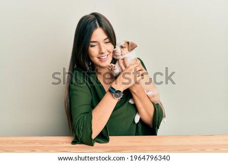 Young hispanic girl smiling happy and hugging dog sitting on the table over isolated white background.