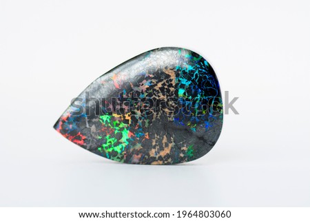 Mined from Queensland fields solid black matrix boulder opal. Red, orange, green, yellow, amber, violet and turquoise color play. Treated, carbonated  to darken and stabilized. Horizontal position. Royalty-Free Stock Photo #1964803060