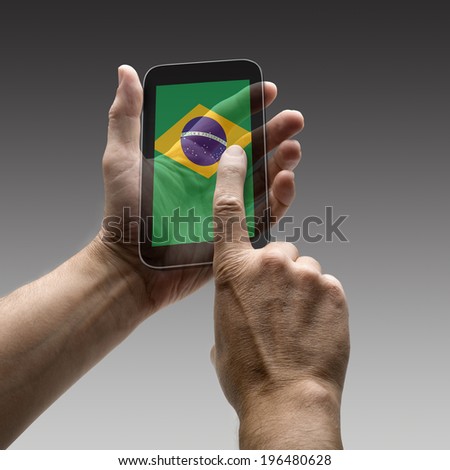 Holding Brazil flag screen smart phone. There is a route for hand and finger.  Royalty-Free Stock Photo #196480628