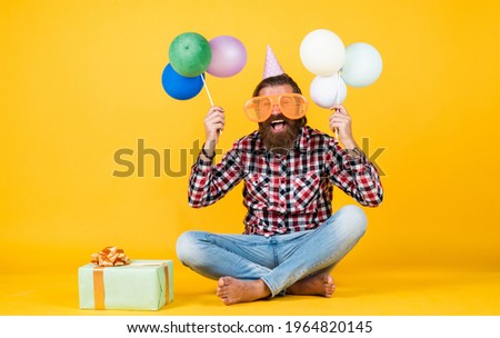 holiday celebration. bearded mature man celebrate birthday party. cheerful man in bday hat hold holiday balloons. gifts and presents concept. have a happy holiday. party time. happy birthday to you