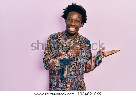 Young african american man wearing casual clothes amazed and smiling to the camera while presenting with hand and pointing with finger. 