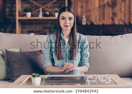 Photo of serious young attractive woman sit sofa calm face wear casual clothes indoors inside house