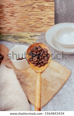 hand with wooden spoon pouring coffee beans into white ceramic cup