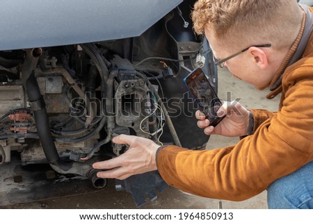 a man takes a photo of a disassembled car engine