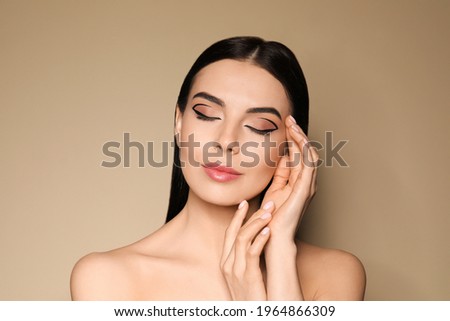 Beautiful woman with black eyeliner on beige background Royalty-Free Stock Photo #1964866309