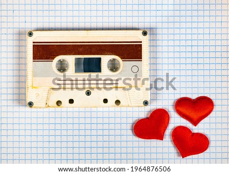 Old Audio Cassette with a Red Hearts on the Square Paper Background closeup
