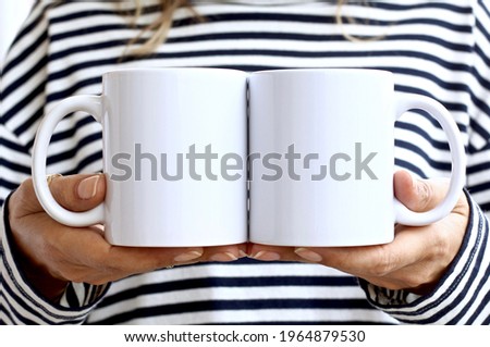 Girl in  striped sweatshirt holding white coffee mug. 2 white porcelain mug mock up. 11 oz mockups for front back design Royalty-Free Stock Photo #1964879530