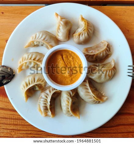 Steam-cooked momos with sauce, Nepalese Traditional Dish Momo. Authentic Cuisine in Nepal momo over a rustic wooden background. Royalty-Free Stock Photo #1964881501