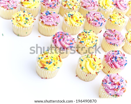 A whole lot of cupcakes with yellow or pink frosting and sprinkles.