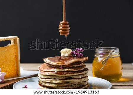 Stack Of Pancakes And Flowing Honey On Wooden Table Black Background. Side View. 