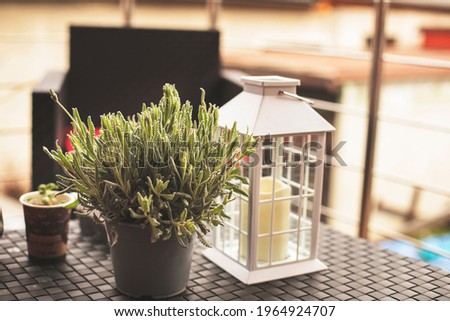 Modern house terrace with lantern, glasses and plant on the table. High quality photo