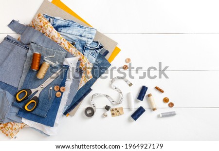 Upcycle old denim garbage. Recycling old jeans. Old blue jeans cut pieces and sewing materials ready for recycling and scissors on white background. Circular economy. Zero waste banner with copy space Royalty-Free Stock Photo #1964927179