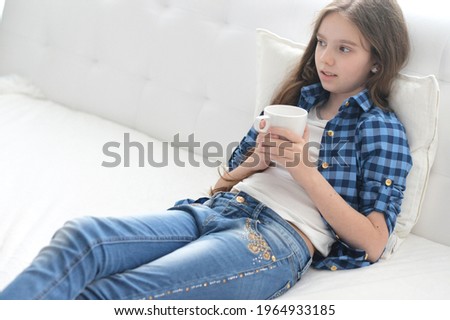 Portrait of cute girl with cup of tea sitting on the floor