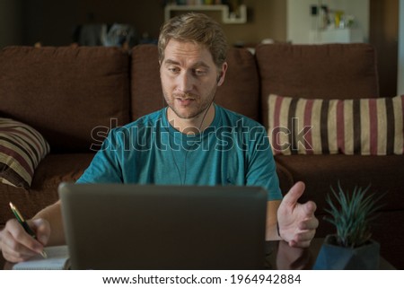Man working from home, on a work video call. Sitting on the floor with his laptop in front of him.