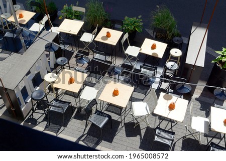 Tables in the garden next to the beer pub are waiting for customers. Full sun, ashtrays on the tables, next to the street. Top view from the floor.                               