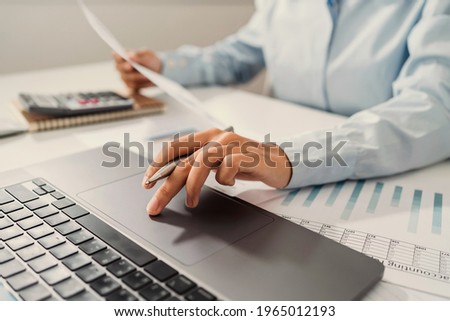 Woman accountant use calculator and computer with holding pen on desk in office. finance and accounting concept