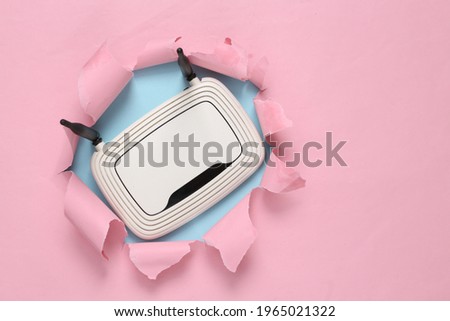 Wi-fi router through torn hole on blue-pink pastel background. Concept art. Pastel color trend. Minimalism