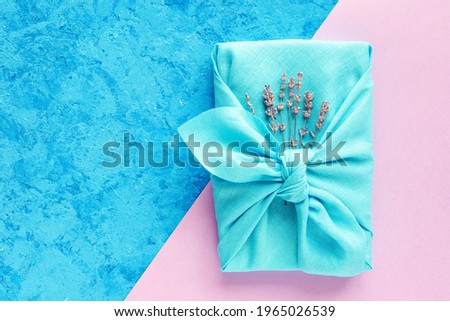 Gift wrapping Japanese furoshiki style on a blue and pink background. Plastic free, zero waste, flat lay, copy space.